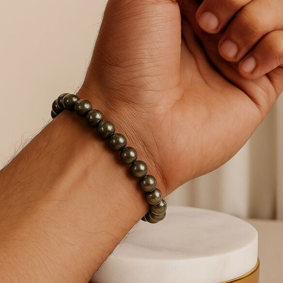 Hand wearing a pyrite stone bracelet
on a neutral background